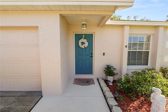 entrance to property with an attached garage and stucco siding