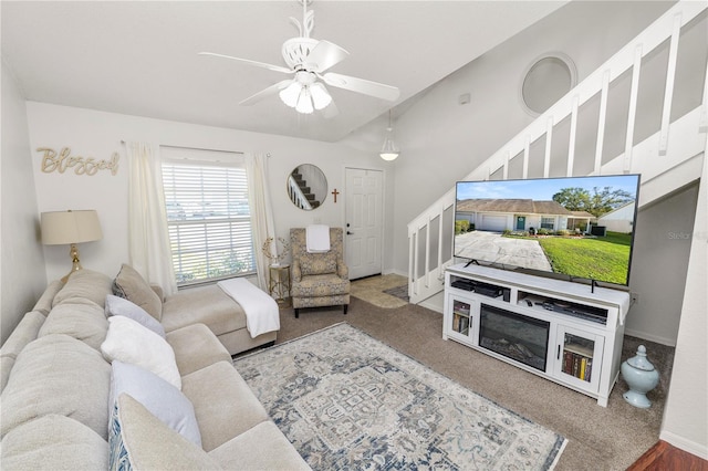 carpeted living room featuring stairs, ceiling fan, and baseboards