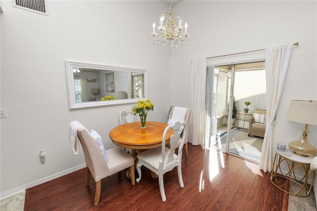 dining area featuring a chandelier, visible vents, baseboards, and wood finished floors