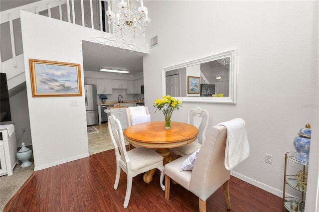 dining room with dark wood-style floors, baseboards, visible vents, and a chandelier