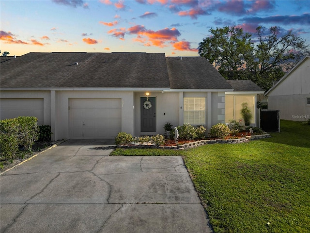 view of front of house with a shingled roof, a lawn, concrete driveway, an attached garage, and stucco siding