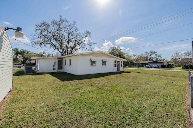 rear view of property with a yard and central AC