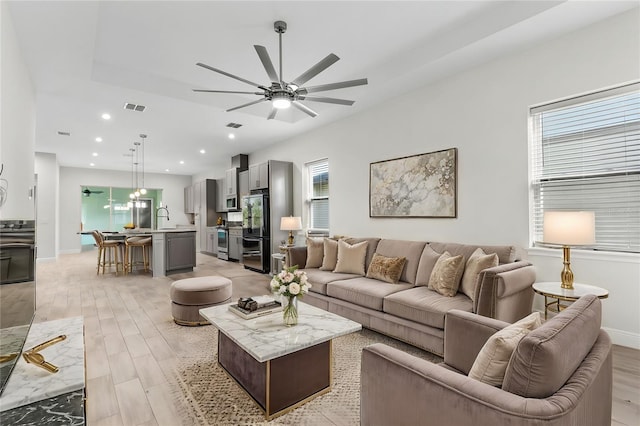 living room featuring a ceiling fan, recessed lighting, baseboards, and light wood finished floors