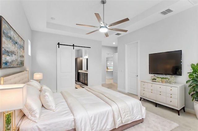 bedroom with ensuite bath, a barn door, visible vents, and baseboards