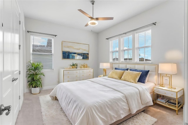 bedroom with light carpet, a ceiling fan, and baseboards