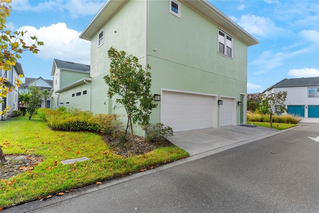 view of side of home with a yard, driveway, and an attached garage