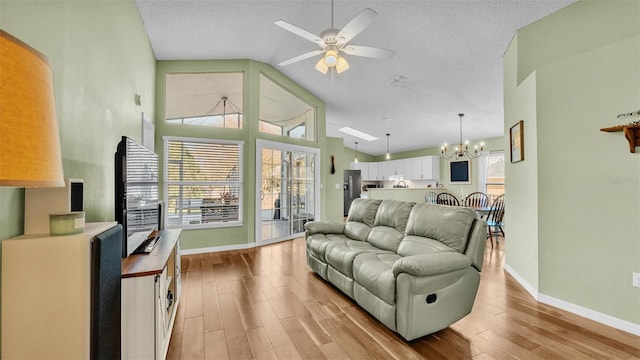 living room with visible vents, ceiling fan with notable chandelier, a textured ceiling, light wood-style floors, and baseboards