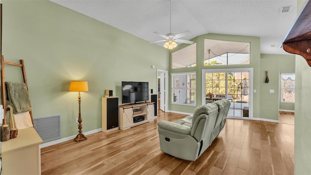 living area featuring visible vents, baseboards, high vaulted ceiling, and light wood-style flooring