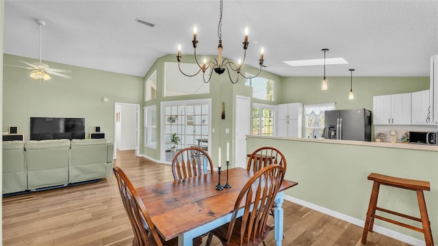 dining room with visible vents, light wood-style flooring, a ceiling fan, and vaulted ceiling