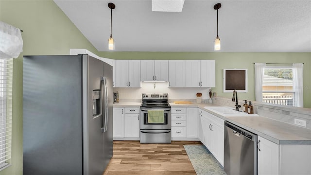 kitchen with a sink, white cabinetry, appliances with stainless steel finishes, light wood finished floors, and light countertops