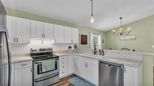 kitchen with a sink, stainless steel appliances, a peninsula, and white cabinets