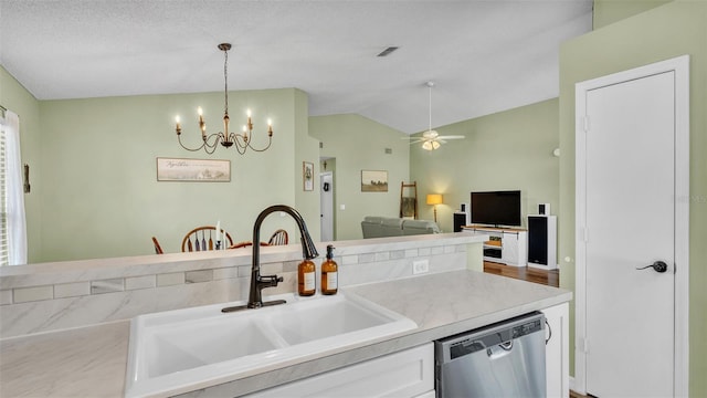 kitchen featuring decorative light fixtures, dishwasher, vaulted ceiling, white cabinets, and a sink