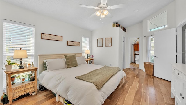 bedroom featuring a ceiling fan, vaulted ceiling, multiple windows, and light wood-style floors