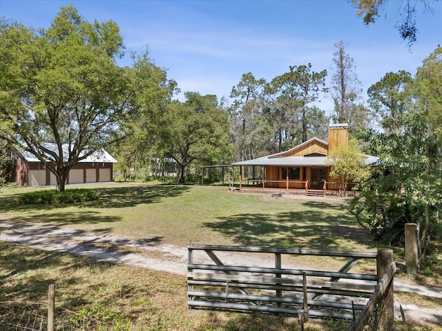 view of yard featuring a garage, a porch, and an outdoor structure