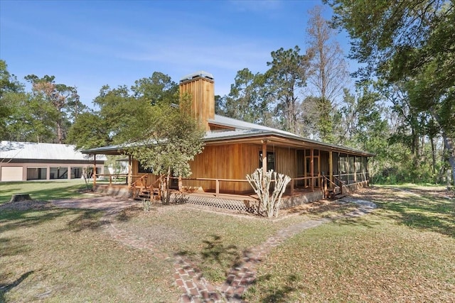 rear view of property with a lawn, a porch, and a chimney