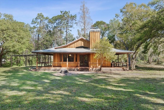 rear view of house featuring metal roof, a yard, and a chimney