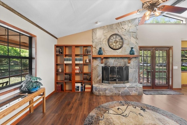 living room featuring a stone fireplace, a ceiling fan, lofted ceiling, and wood finished floors