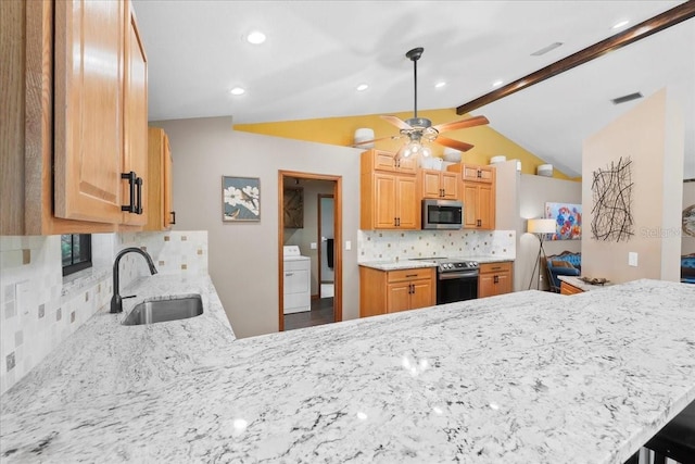 kitchen with vaulted ceiling with beams, ceiling fan, washer / dryer, appliances with stainless steel finishes, and a sink