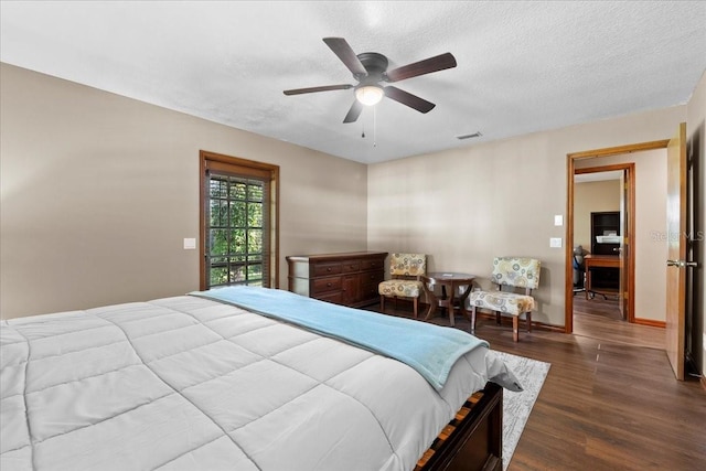 bedroom featuring a ceiling fan, baseboards, visible vents, dark wood-style flooring, and a textured ceiling