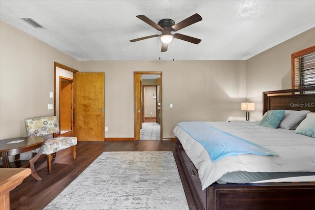 bedroom with a ceiling fan, wood finished floors, visible vents, baseboards, and a textured ceiling