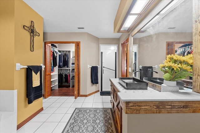 kitchen featuring light tile patterned floors, baseboards, and a sink