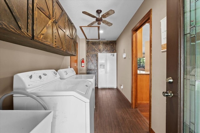 clothes washing area featuring dark wood-type flooring, a ceiling fan, washer and dryer, cabinet space, and baseboards