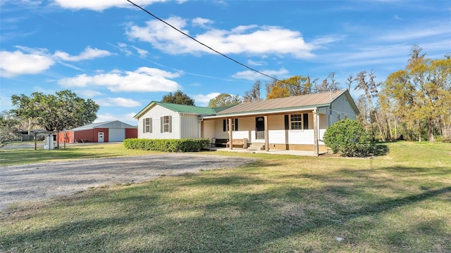 view of front of home with driveway, metal roof, and a front lawn