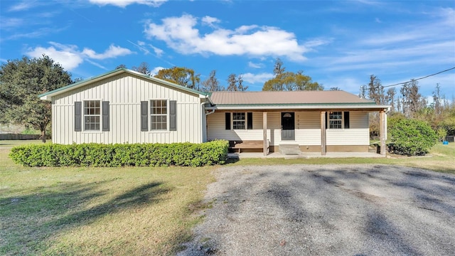 view of front of property featuring a porch, board and batten siding, metal roof, and a front yard