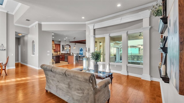 living area featuring crown molding, light wood-style flooring, baseboards, and visible vents