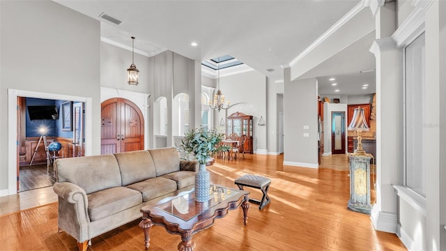 living room featuring visible vents, arched walkways, light wood-style floors, and crown molding