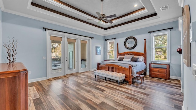 bedroom featuring visible vents, access to outside, a tray ceiling, wood finished floors, and crown molding