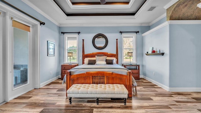 bedroom featuring a tray ceiling, access to exterior, and light wood-style flooring