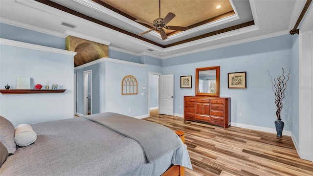 bedroom with visible vents, crown molding, a tray ceiling, and wood finished floors