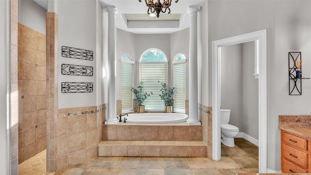 bathroom featuring a chandelier, toilet, a garden tub, vanity, and ornate columns