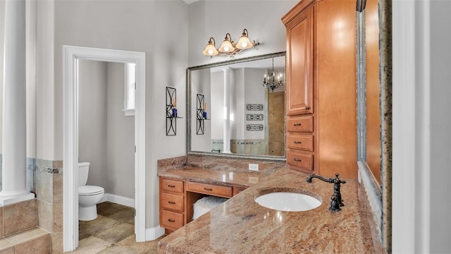 bathroom with baseboards, toilet, vanity, and ornate columns