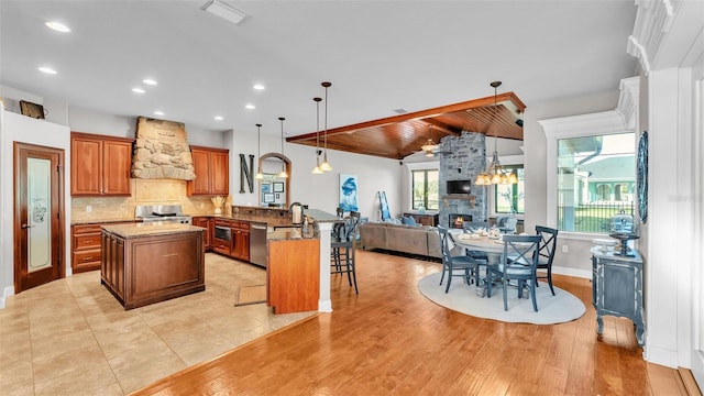 kitchen featuring a kitchen island, a peninsula, range, custom exhaust hood, and stainless steel dishwasher