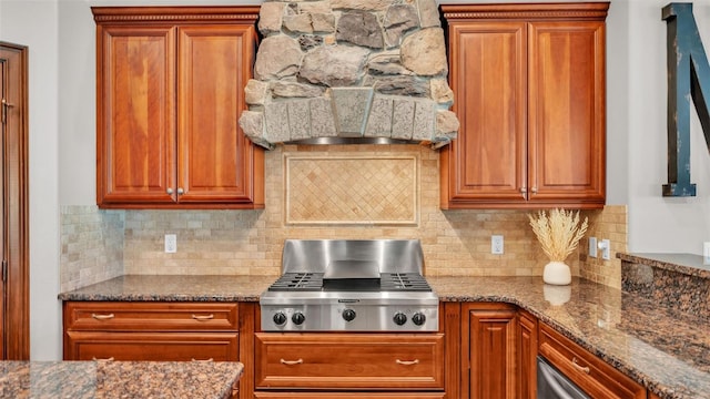 kitchen featuring premium range hood, brown cabinets, dark stone counters, stainless steel gas stovetop, and tasteful backsplash