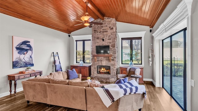 living area featuring wood finished floors, vaulted ceiling with beams, a fireplace, and a healthy amount of sunlight