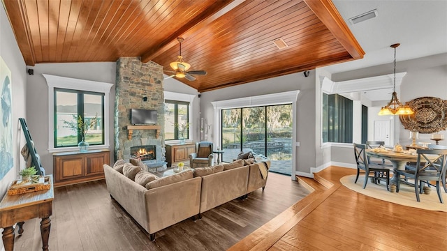 living area with hardwood / wood-style floors, a stone fireplace, lofted ceiling with beams, and wood ceiling