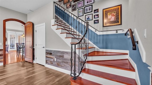 staircase with arched walkways and wood finished floors