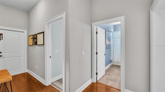 corridor featuring dark wood-type flooring and baseboards