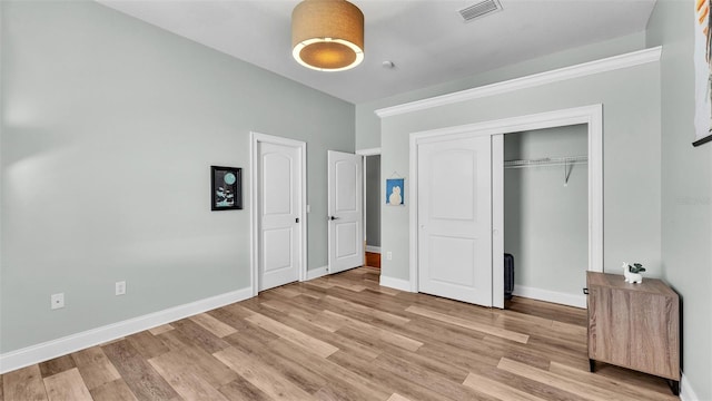 unfurnished bedroom with visible vents, baseboards, light wood-style floors, and a closet