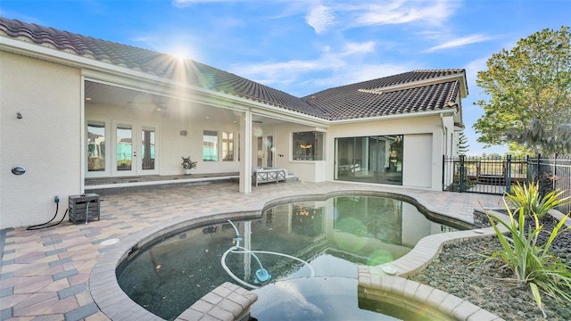 rear view of house featuring fence, a tiled roof, stucco siding, french doors, and a patio area