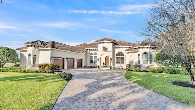 mediterranean / spanish-style house with stucco siding, a front lawn, a garage, a tile roof, and decorative driveway