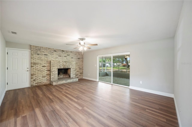 unfurnished living room featuring visible vents, a ceiling fan, wood finished floors, baseboards, and a brick fireplace