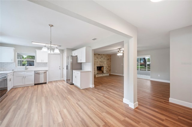 kitchen featuring tasteful backsplash, open floor plan, a wealth of natural light, a fireplace, and stainless steel appliances