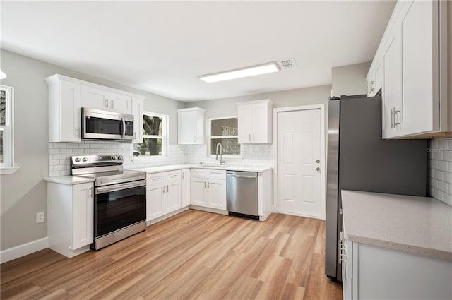 kitchen featuring white cabinetry, light wood-style flooring, appliances with stainless steel finishes, and a sink