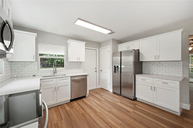 kitchen featuring stainless steel appliances, light countertops, light wood-style floors, and a sink