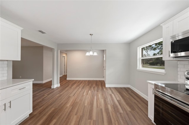 kitchen with visible vents, light wood finished floors, decorative backsplash, light countertops, and appliances with stainless steel finishes