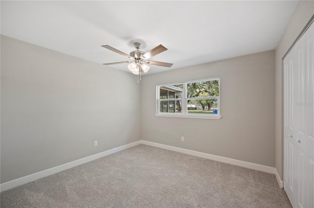 unfurnished bedroom with a closet, light colored carpet, a ceiling fan, and baseboards